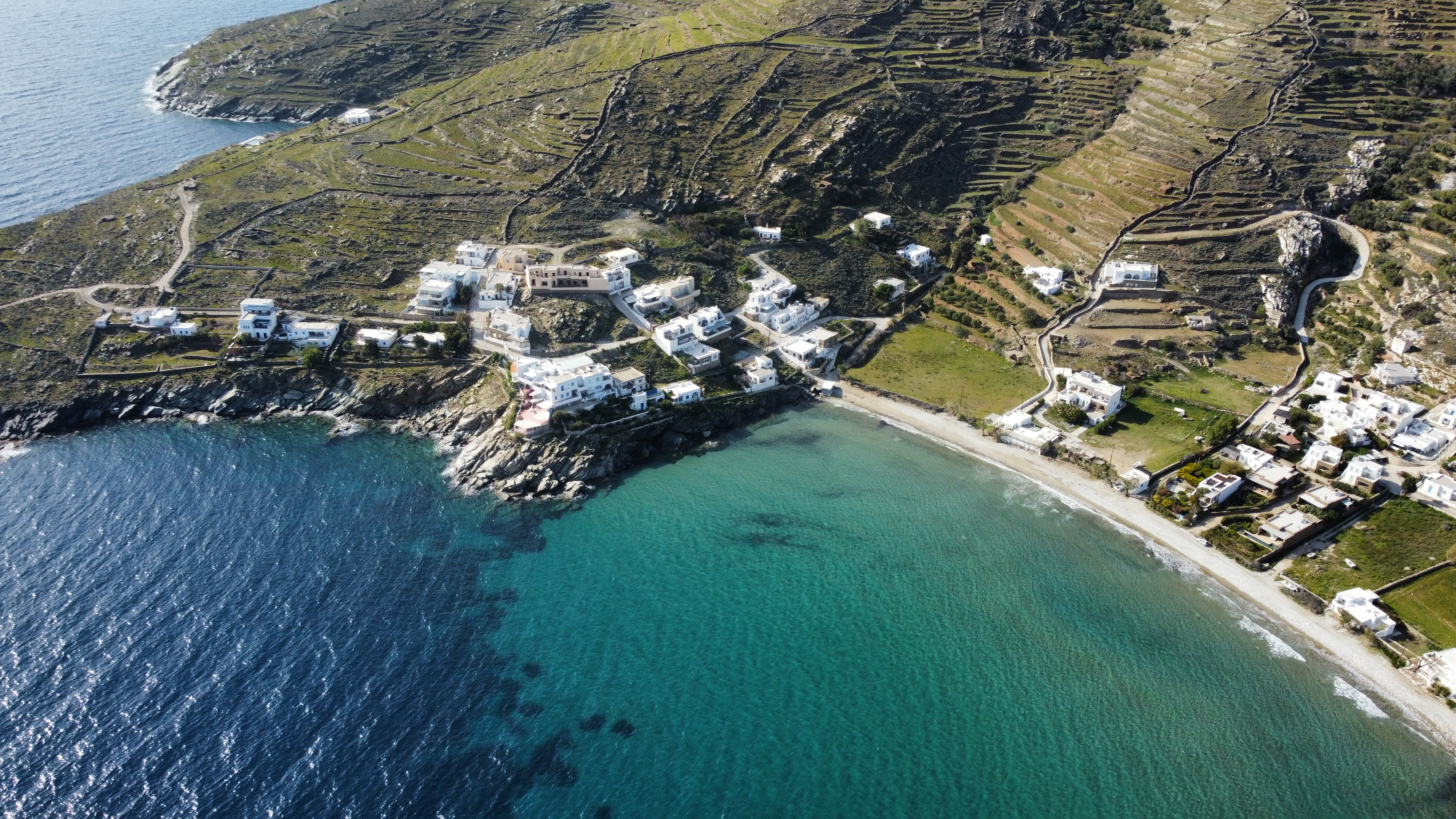 Panoramic view of the whitewashed village of Kardiani Tinos, cascading down a hill towards the Aegean Sea.